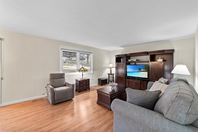 living room with light wood-type flooring, baseboards, and visible vents