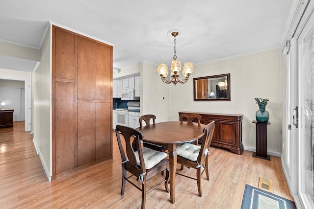 dining area featuring light wood finished floors, visible vents, an inviting chandelier, ornamental molding, and baseboards