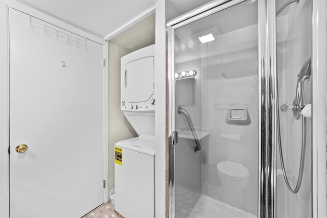 full bath featuring toilet, a shower stall, and stacked washer and clothes dryer