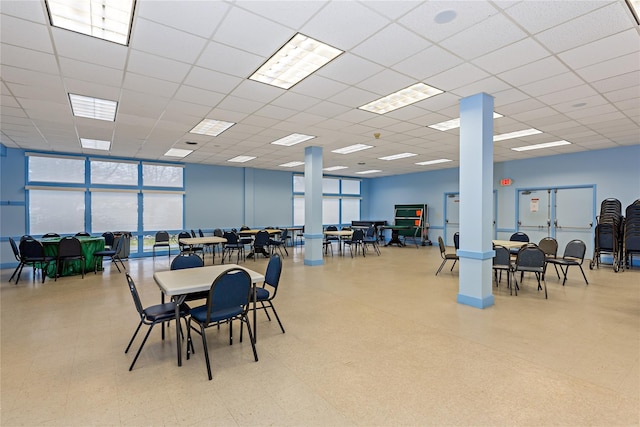 dining space with a healthy amount of sunlight, a drop ceiling, and tile patterned floors