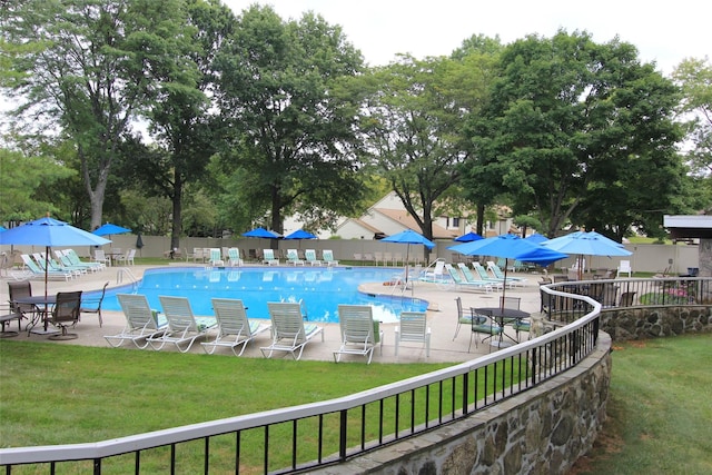 community pool featuring a lawn, a patio area, and fence