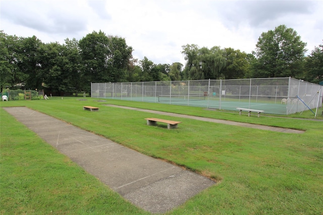 surrounding community featuring a tennis court, fence, and a lawn