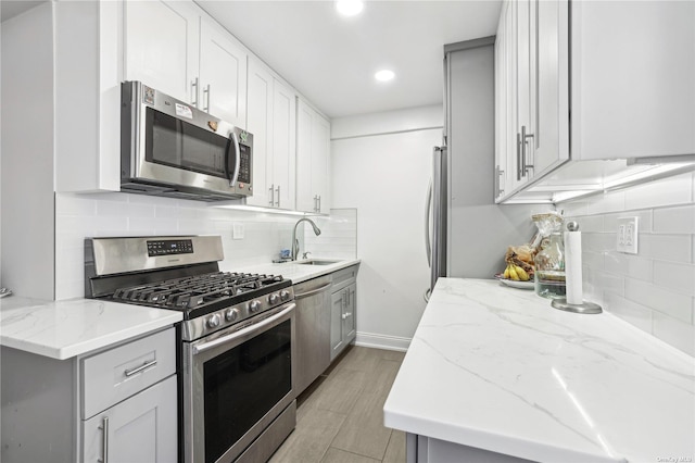 kitchen with stainless steel appliances, light stone countertops, sink, and backsplash