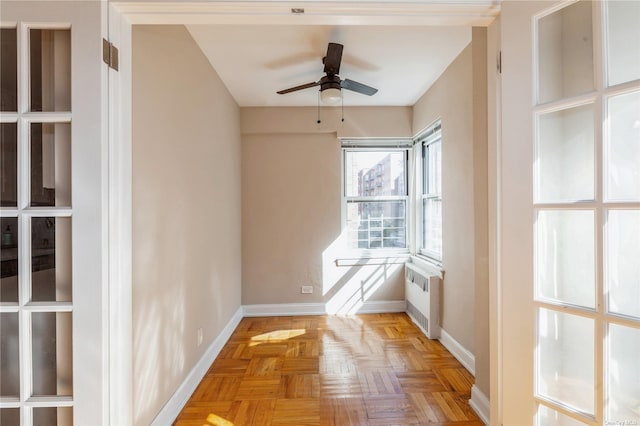 empty room featuring light parquet floors, radiator heating unit, and ceiling fan