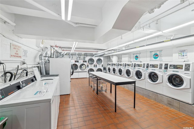 clothes washing area with stacked washer and clothes dryer, dark tile patterned flooring, and independent washer and dryer