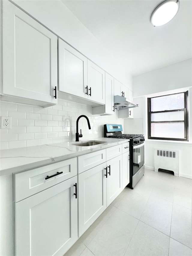 kitchen with sink, stainless steel gas stove, white cabinetry, radiator, and backsplash