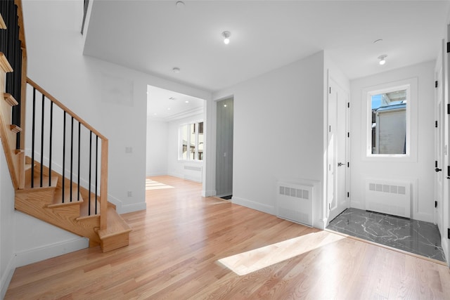 entrance foyer featuring radiator, a wealth of natural light, and light hardwood / wood-style flooring