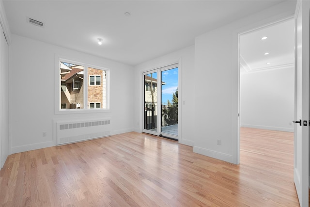 spare room with radiator heating unit and light hardwood / wood-style floors