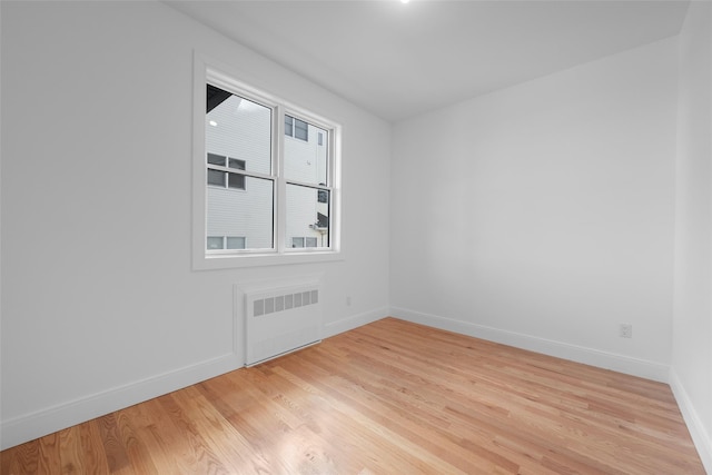 unfurnished room featuring radiator heating unit and light hardwood / wood-style floors