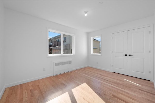 unfurnished bedroom with radiator, light hardwood / wood-style floors, and a closet