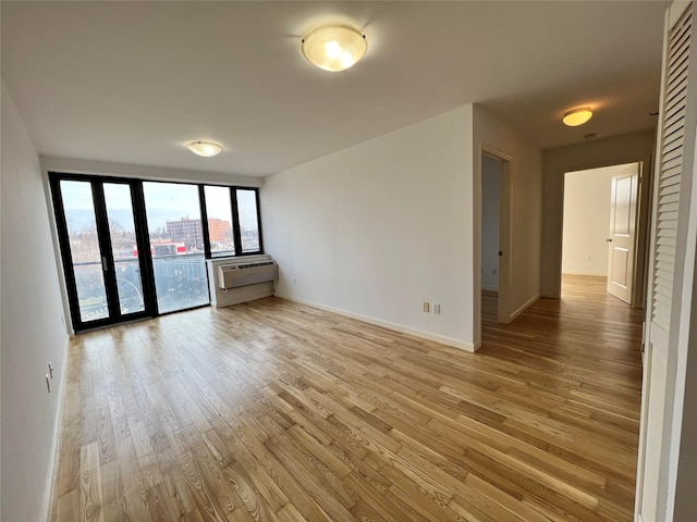 spare room with a wall mounted AC and light wood-type flooring