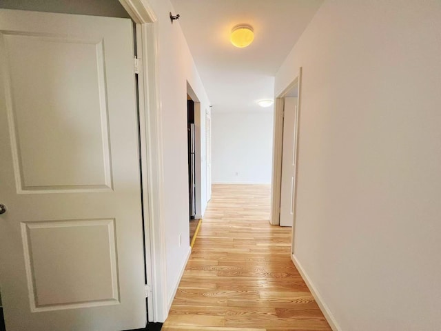 corridor with light wood-style floors and baseboards