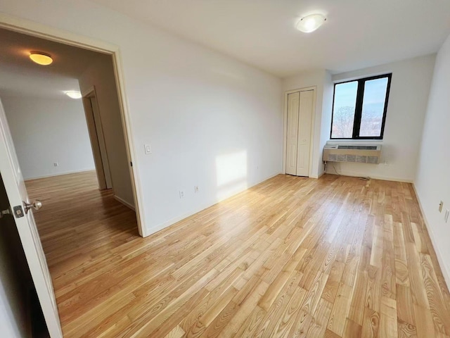 empty room featuring a wall mounted AC and light wood-type flooring