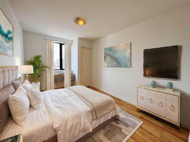 bedroom with a closet, baseboards, and light wood finished floors