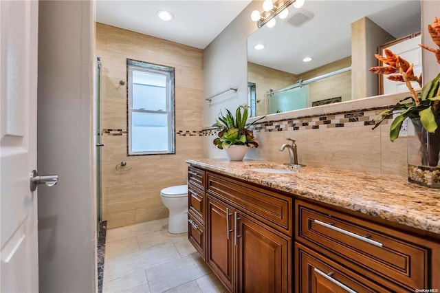 full bathroom with tile walls, visible vents, toilet, vanity, and tile patterned flooring