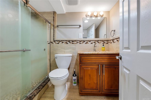 full bathroom featuring toilet, vanity, visible vents, tile walls, and a stall shower