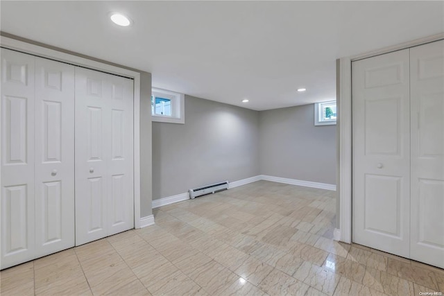 basement featuring plenty of natural light, a baseboard radiator, and baseboards