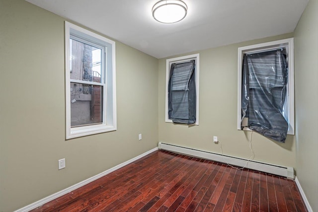 spare room featuring dark wood-type flooring and a baseboard radiator