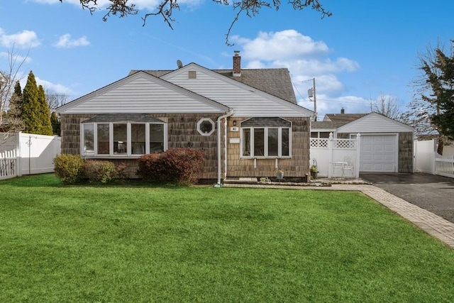 view of front facade featuring a garage, aphalt driveway, a front yard, and an outdoor structure