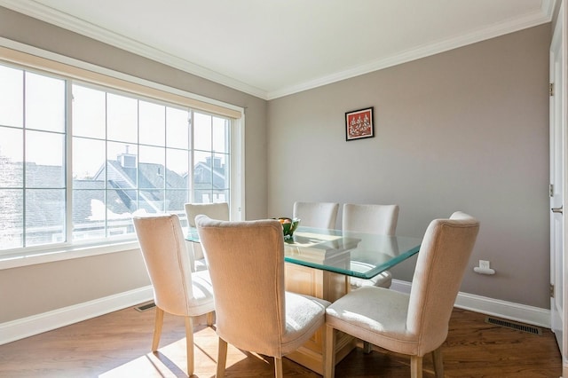 dining room featuring ornamental molding, wood finished floors, visible vents, and baseboards