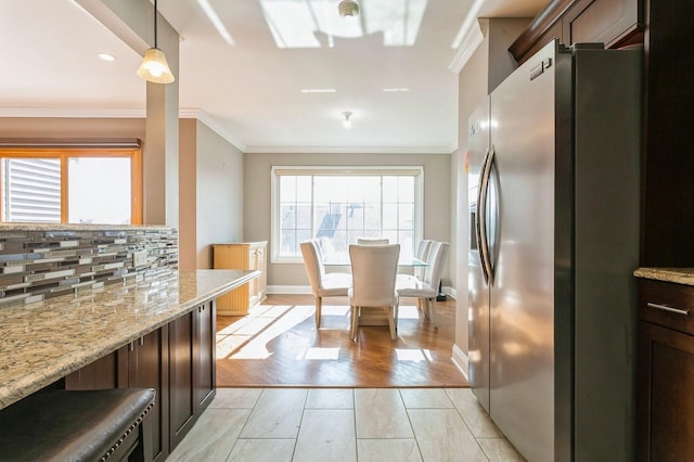 kitchen with dark brown cabinetry, stainless steel fridge with ice dispenser, and light stone countertops