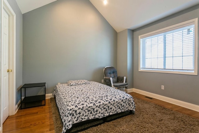 bedroom with lofted ceiling, baseboards, and dark wood-style flooring