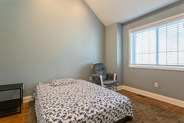 bedroom featuring visible vents, baseboards, vaulted ceiling, and wood finished floors