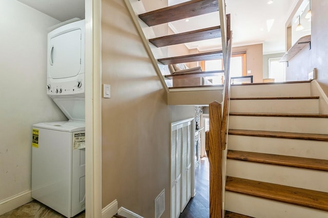 staircase with stacked washer and dryer, visible vents, and baseboards