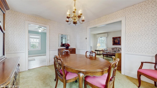 dining space featuring light carpet, a healthy amount of sunlight, wainscoting, and wallpapered walls