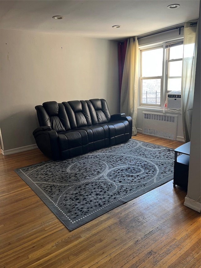 living room with cooling unit, radiator heating unit, and hardwood / wood-style floors