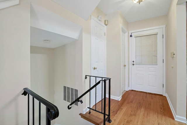 hallway with an upstairs landing, light wood-type flooring, and baseboards