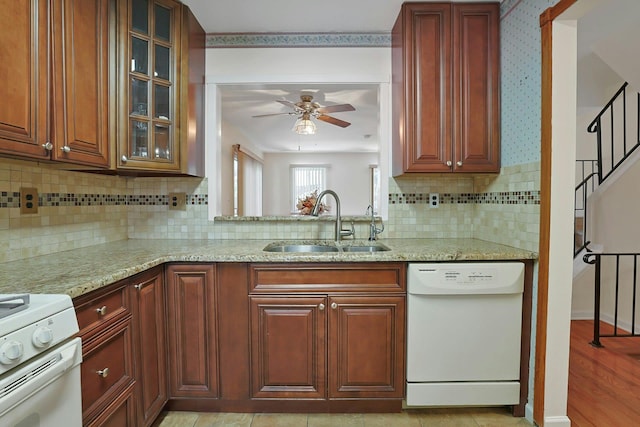 kitchen with a sink, glass insert cabinets, white appliances, and light stone countertops