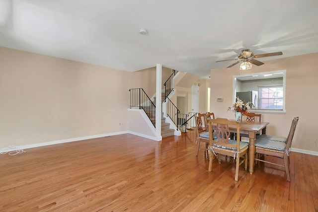 dining room with stairs, light wood-style floors, baseboards, and ceiling fan