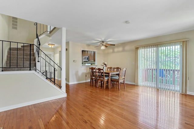 dining area with stairs, baseboards, wood-type flooring, and ceiling fan