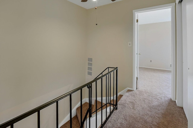 hall featuring carpet, an upstairs landing, and baseboards