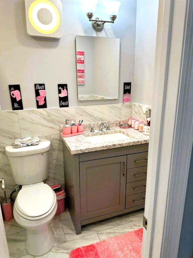 bathroom featuring tile walls, toilet, and vanity