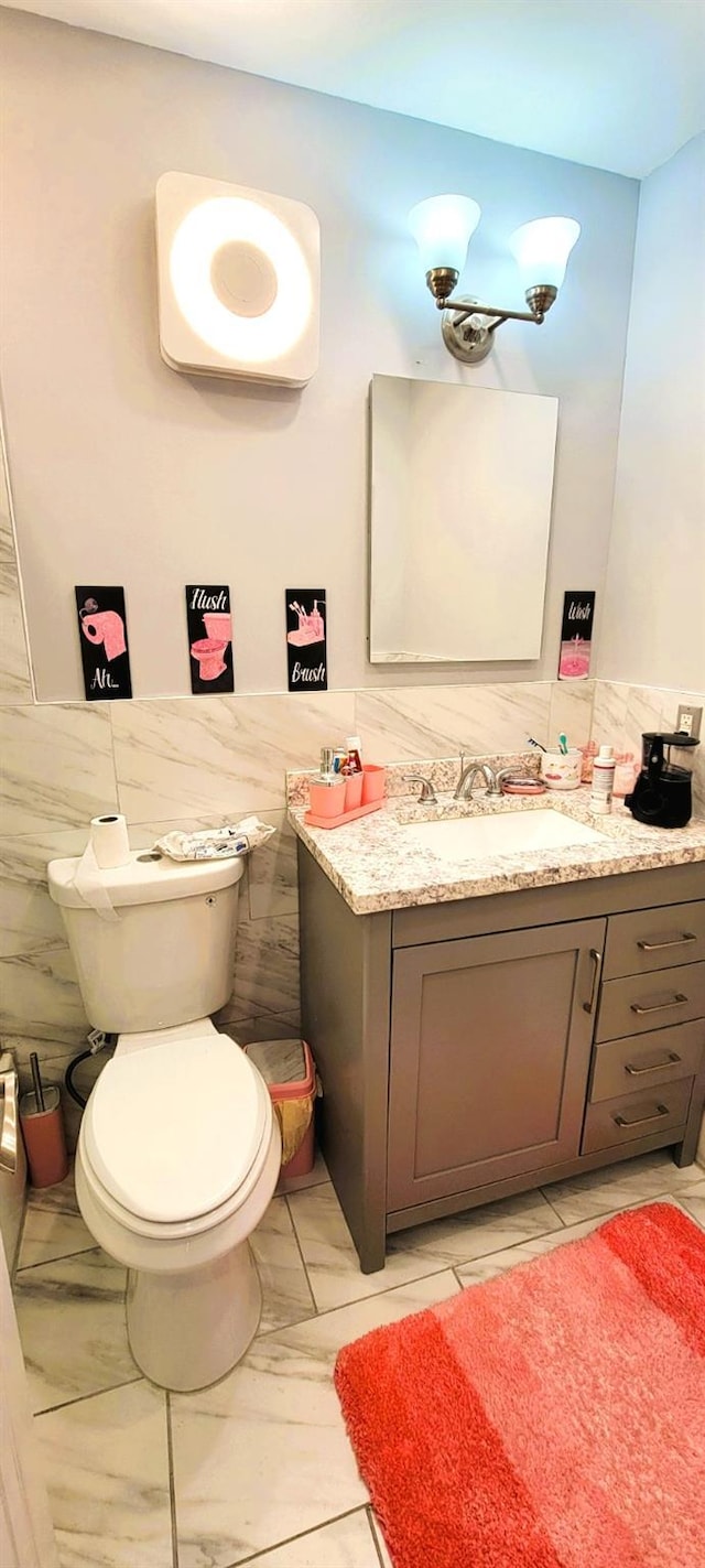 bathroom featuring tile walls, vanity, and toilet