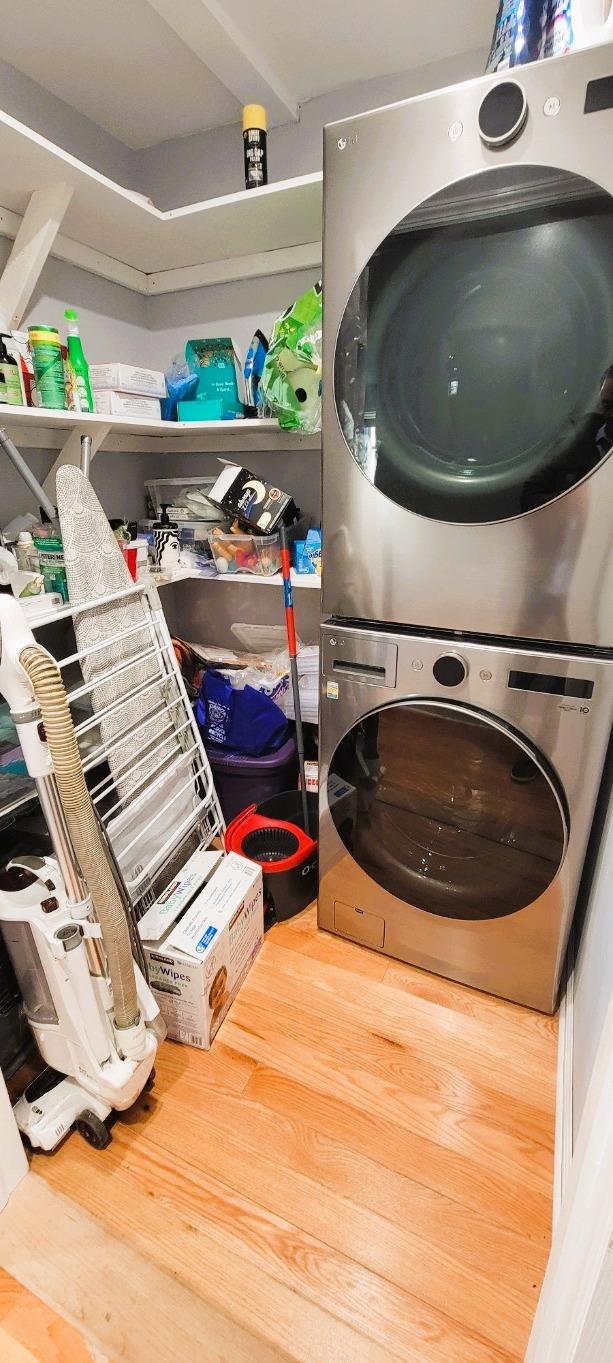 laundry area featuring hardwood / wood-style flooring and stacked washer / drying machine