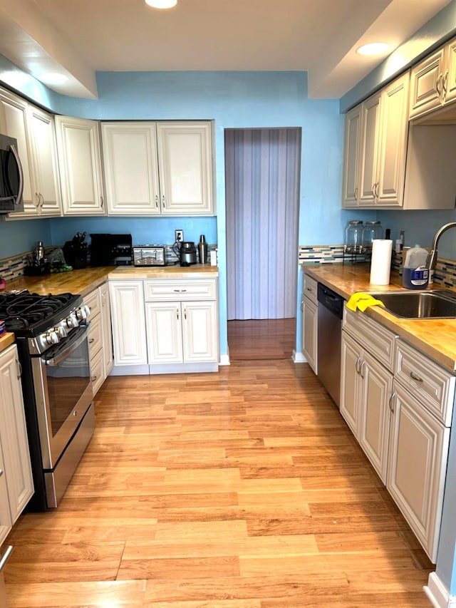 kitchen featuring wooden counters, appliances with stainless steel finishes, sink, and light hardwood / wood-style floors