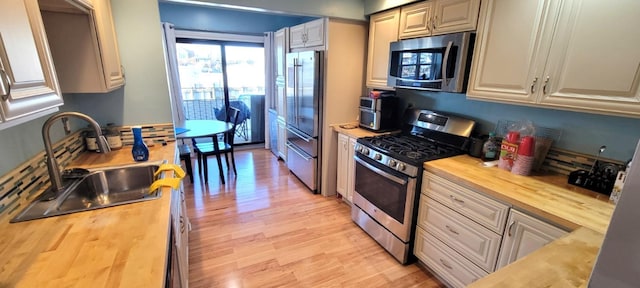 kitchen featuring light wood-type flooring, stainless steel appliances, butcher block counters, and sink