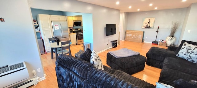 living room featuring a wall unit AC, a baseboard heating unit, and light hardwood / wood-style flooring