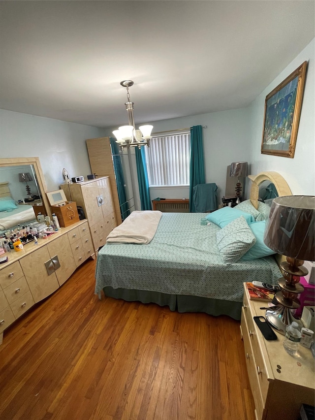 bedroom with hardwood / wood-style floors and an inviting chandelier