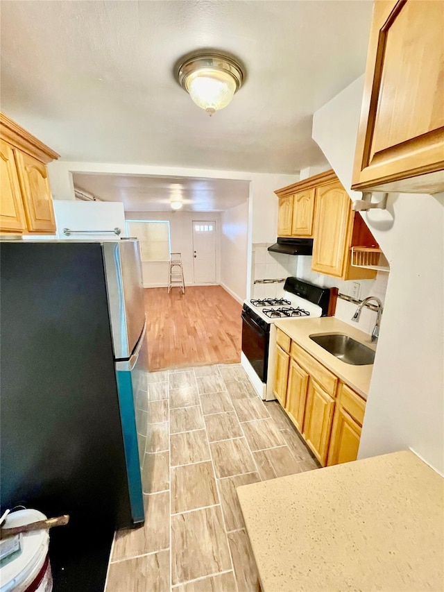 kitchen featuring sink, stainless steel fridge, range with gas cooktop, and light brown cabinets