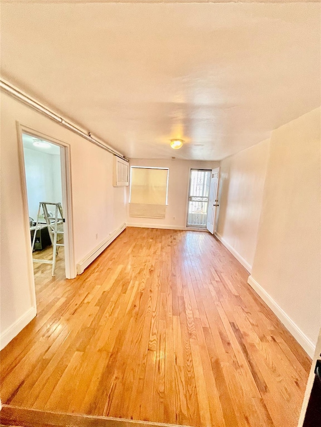 unfurnished room with light hardwood / wood-style flooring and a baseboard heating unit