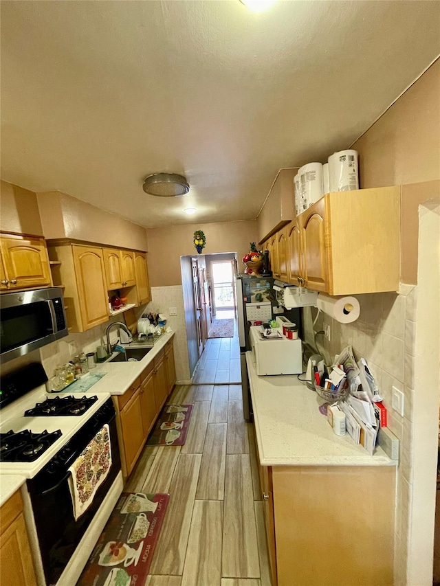 kitchen featuring gas stove, backsplash, and sink