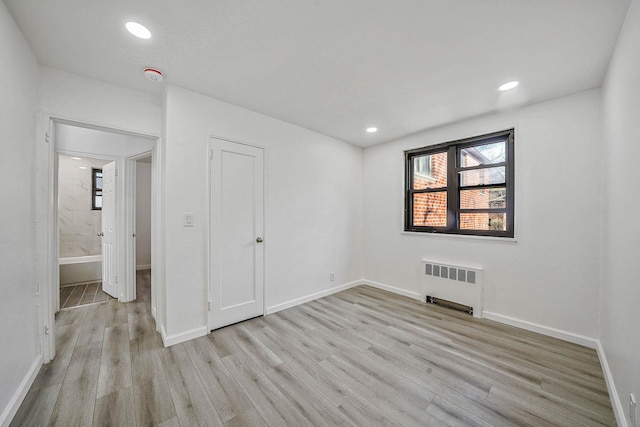 spare room featuring radiator heating unit and light hardwood / wood-style floors