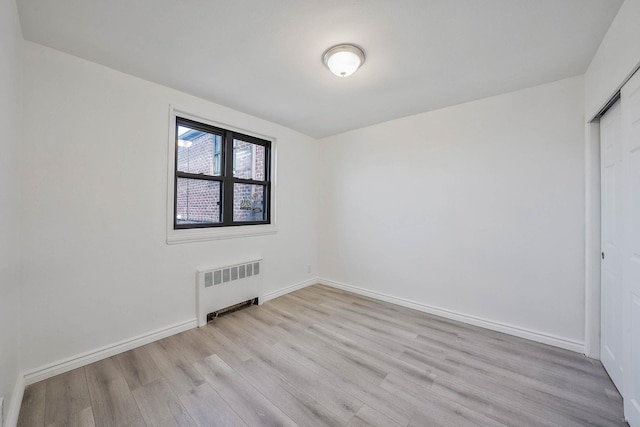 empty room with radiator heating unit and light hardwood / wood-style floors