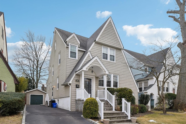 view of front of house featuring a garage, driveway, a shingled roof, and an outbuilding