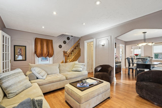 living room featuring light wood-style floors, stairs, arched walkways, and recessed lighting