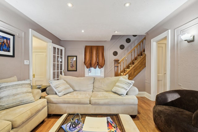 living room featuring light wood-style flooring, stairs, baseboards, and recessed lighting